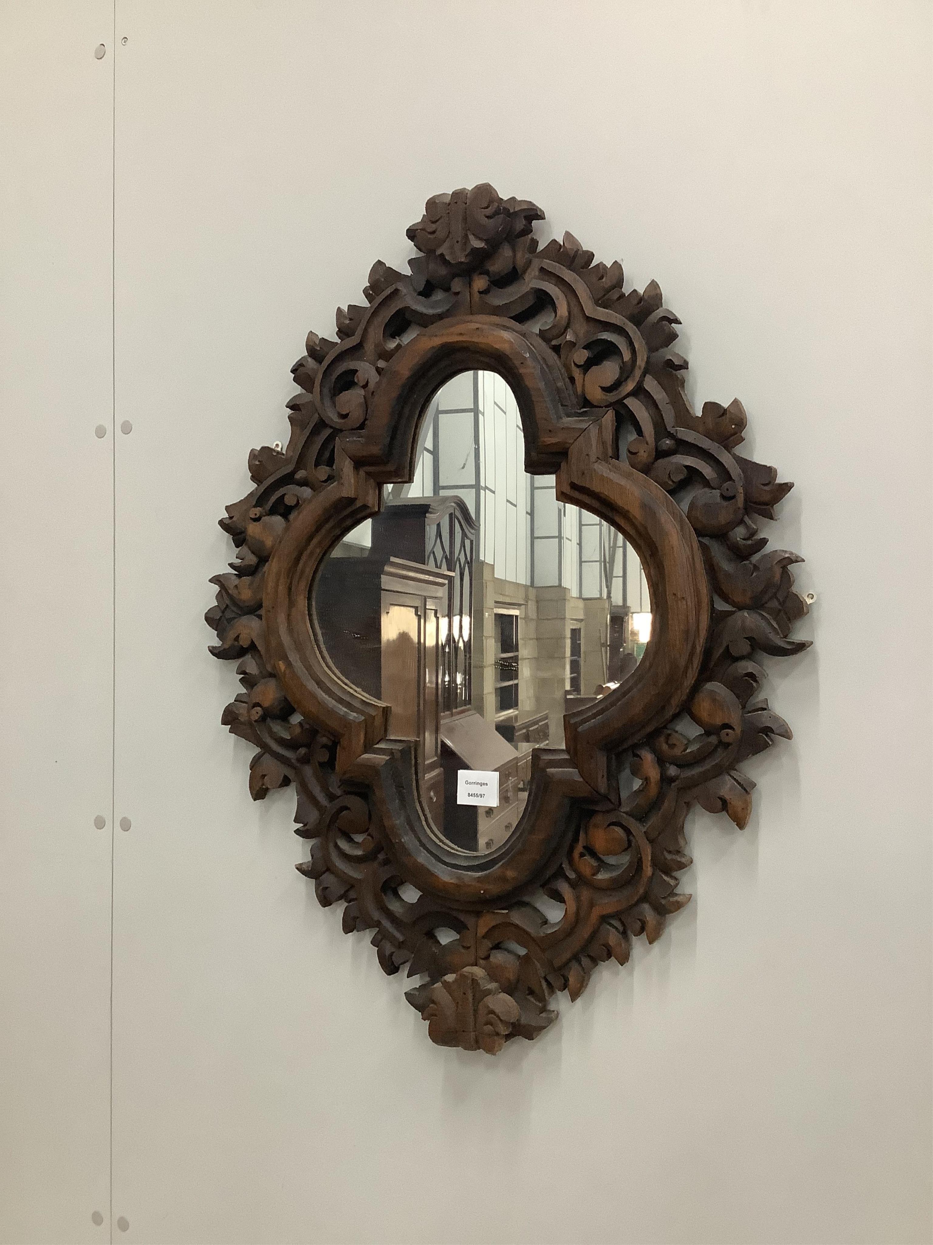 An 18th century style shaped oval carved pine wall mirror, width 61cm, height 79cm. Condition - fair